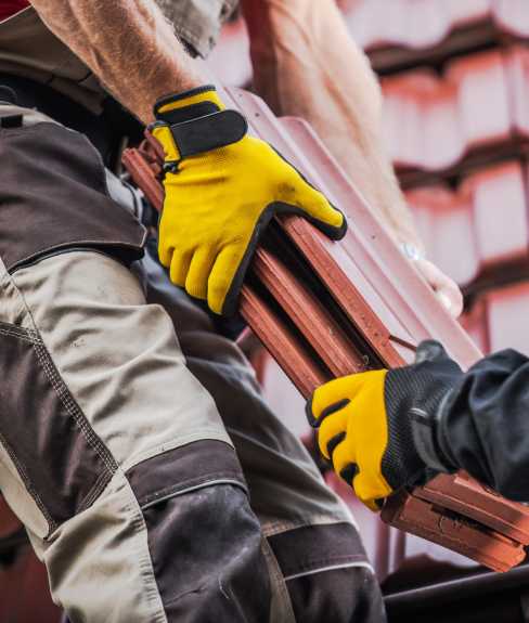 Men passing roof tile to another man on a later