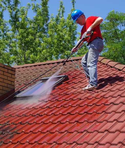 Man cleaning a roof with a pressure washer.