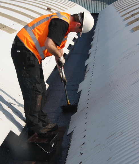 man coating a roof with sealant